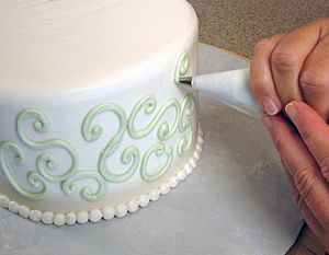 Piping buttercream onto cake