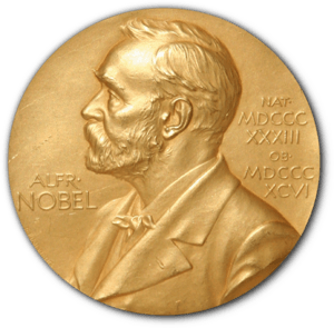 A golden medallion with an embossed image of Alfred Nobel facing left in profile. To the left of the man is the text "ALFR•" then "NOBEL", and on the right, the text (smaller) "NAT•" then "MDCCCXXXIII" above, followed by (smaller) "OB•" then "MDCCCXCVI" below.