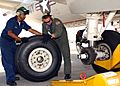 Two man replace a main landing gear tire of a plane