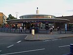 A grey building with a rectangular, dark blue sign reading "SOUTHGATE STATION" in white letters all under a light blue sky with white clouds