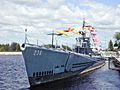 A submarine tied to a dock, flying many signal flags.