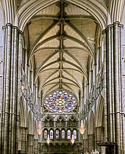 The inside of Westminster Abbey north transept, with a high vaulted ceiling and a rose window at the end.