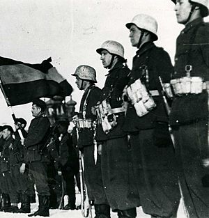 Fotografía de la bandera española presidiendo un acto de la División Azul