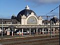 Train station with large, domed building and a high-speed train at the platform