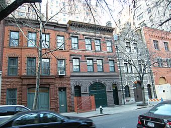 A row of four brick and stone buildings in a city with large rounded double doors at street level