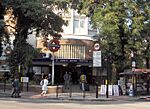 A brown-bricked building with a rectangular, dark blue sign reading "ST. JOHN'S WOOD STATION" in white letters all under a light blue sky